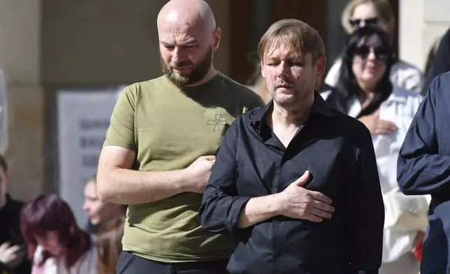 Yaroslav Bazylevych, right, prays during the funeral ceremony for his family members in Lviv, Ukraine, Friday, Sept. 6, 2024. Bazylevych's wife Yevgenia and their three daughters - Darina, 18, Emilia, 7, and Yaryna, 21 - were killed in Wednesday's Russian missile attack. (AP Photo/Mykola Tys)