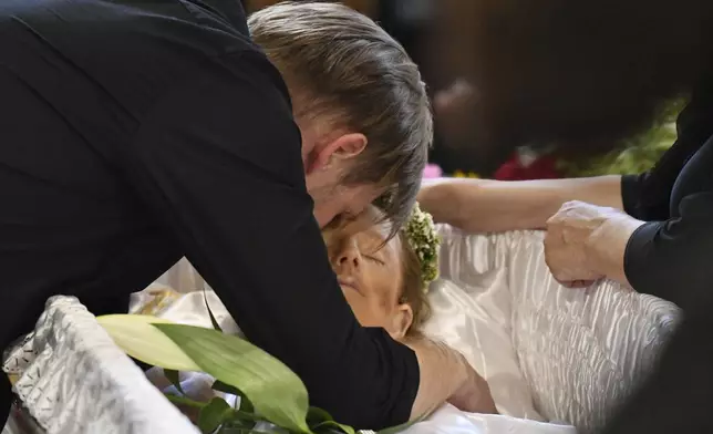 Yaroslav Bazylevych mourns over the coffins of his family members during the funeral service in the Garrison Church in Lviv, Ukraine, Friday, Sept. 6, 2024. Bazylevych's wife Yevgenia and their three daughters - Darina, 18, Emilia, 7, and Yaryna, 21 - were killed in Wednesday's Russian missile attack. (AP Photo/Mykola Tys)