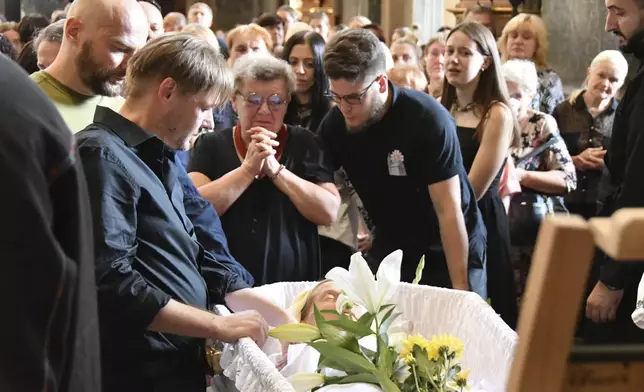 Yaroslav Bazylevych, second left, mourns at the coffins of his family during their funeral service in the Garrison Church in Lviv, Ukraine, Friday, Sept. 6, 2024. Bazylevych's wife Yevgenia and their three daughters - Darina, 18, Emilia, 7, and Yaryna, 21 - were killed in Wednesday's Russian missile attack. (AP Photo/Mykola Tys)