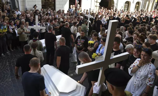 People carry the coffins of the family members of Yaroslav Bazylevych during the funeral procession in Lviv, Ukraine, Friday, Sept. 6, 2024. Bazylevych's wife Yevgenia and their three daughters - Darina, 18, Emilia, 7, and Yaryna, 21 - were killed in Wednesday's Russian missile attack. (AP Photo/Mykola Tys)