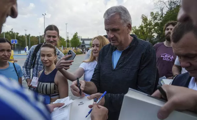 U.S. historian and author Timothy Snyder gives autographs on his books before charity run to raise awareness on Ukrainian prisoners of war held by Russia, in Kyiv, Ukraine, Saturday, Sept. 14, 2024. (AP Photo/Evgeniy Maloletka)