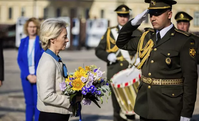 President of the European Commission Ursula von der Leyen, left, holds a bouquet of flowers to place at a wall commemorating the fallen Ukrainian soldiers in the war with Russia, in Kyiv, Ukraine, Friday, Sept. 20, 2024. (Christoph Soeder, Pool via AP)