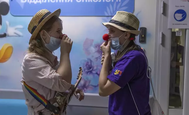 Vladyslava Kulinich, right, Tetiana Nosova, who have the clown names Lala and Zhuzha, prepare to perform at Okhmatdyt children's hospital in Kyiv, Ukraine, Thursday Sept. 19, 2024. (AP Photo/Anton Shtuka)