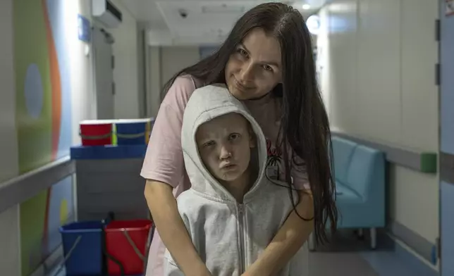 Kira Vertetska, 8 and her mother Daria pose for a photo in a corridor at Okhmatdyt children's hospital in Kyiv, Ukraine, Thursday Sept. 19, 2024. (AP Photo/Anton Shtuka)