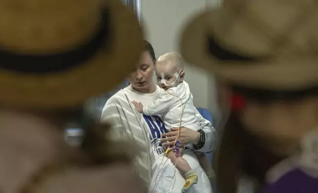 Michael Bilyk, is held by his mother Antonina Malyshko, as he is visited by Zhuzha and Lala from the volunteer group the "Bureau of Smiles and Support" at Okhmatdyt children's hospital in Kyiv, Ukraine, Thursday Sept. 19, 2024. (AP Photo/Anton Shtuka)