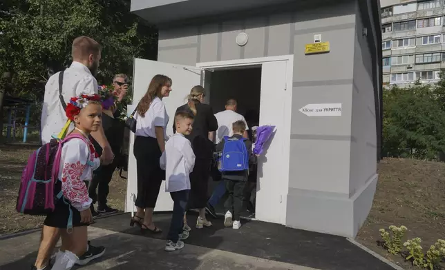 Schoolchildren and their parents enter an underground school on the first day at school in Kharkiv, Ukraine, Monday, Sept. 2, 2024. The purpose-built "bunker school" aims to provide a learning environment safe from Russian everyday airstrikes. (AP Photo/Andrii Marienko)