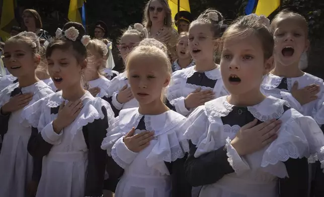 Schoolgirls sing the national anthem on the first day at school in a cadet lyceum in Kyiv, Ukraine, Monday, Sept. 2, 2024. Children and students went to school despite the fact that Kyiv was hit by massive Russian missile barrage early in the morning, causing fires, damaged buildings and infrastructure objects. (AP Photo/Efrem Lukatsky)