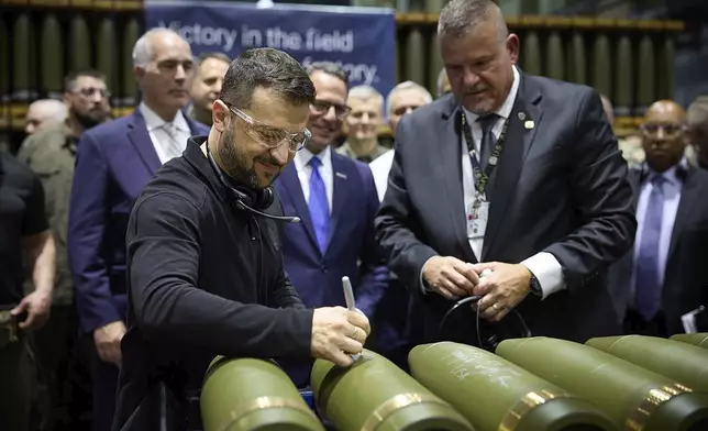 In this image provided by the Office of the Ukrainian Presidency, Ukrainian President Volodymyr Zelenskyy, left, is watched by Rich Hansen, the commander's representative for the Scranton Army Ammunition Plant, while signing military ordnance in Scranton, Pa., Sunday, Sept. 22, 2024. (Office of the Ukrainian Presidency via AP)