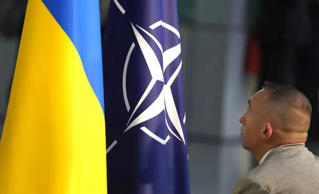 FILE - A member of protocol sets up the NATO and Ukrainian flags prior to a media conference of Ukraine's President Volodymyr Zelenskyy and NATO Secretary General Jens Stoltenberg during a meeting of NATO defense ministers at NATO headquarters in Brussels, Wednesday, Oct. 11, 2023. (AP Photo/Virginia Mayo, File)