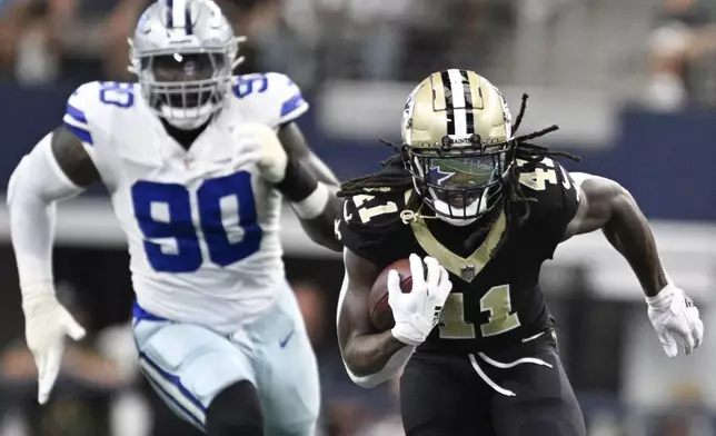 New Orleans Saints running back Alvin Kamara (41) breaks away with Dallas Cowboys defensive end DeMarcus Lawrence (90) in tow while running for a long touchdown during the first half of an NFL football game, Sunday, Sept. 15, 2024, in Arlington, Texas. (AP Photo/Tony Gutierrez)