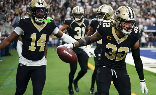 New Orleans Saints safety Tyrann Mathieu (32) reacts with teammates, including Kool-Aid McKinstry (14) and Jordan Howden (31) after intercepting a pass by Dallas Cowboys quarterback Dak Prescott during the second half of an NFL football game, Sunday, Sept. 15, 2024, in Arlington, Texas. (AP Photo/Jeffrey McWhorter)