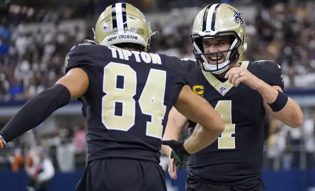 New Orleans Saints wide receiver Mason Tipton (84) and quarterback Derek Carr (4) react after a touchdown run by teammate Alvin Kamara during the first half of an NFL football game against the Dallas Cowboys, Sunday, Sept. 15, 2024, in Arlington, Texas. (AP Photo/Tony Gutierrez)