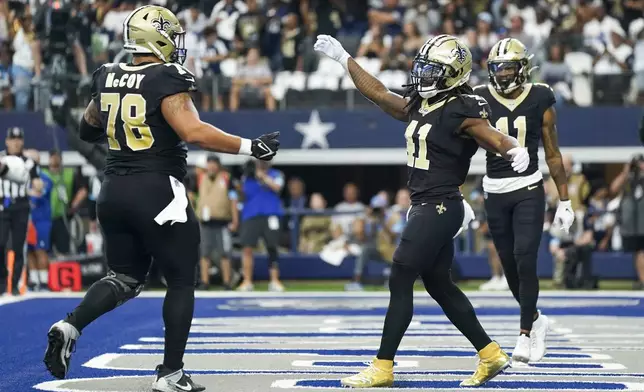 New Orleans Saints running back Alvin Kamara (41) celebrates his first quarter touchdown run with teammate center Erik McCoy (78) during the first half of an NFL football game against the Dallas Cowboys, Sunday, Sept. 15, 2024, in Arlington, Texas. (AP Photo/Jeffrey McWhorter)