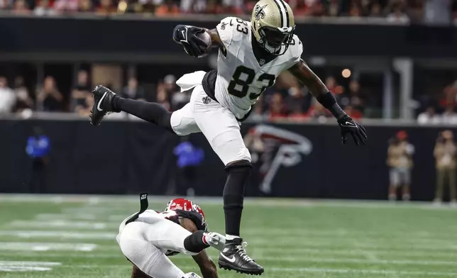 New Orleans Saints tight end Juwan Johnson (83) lewaps over Atlanta Falcons cornerback Dee Alford (20) during the second half of an NFL football game, Sunday, Sept. 29, 2024, in Atlanta. (AP Photo/Butch Dill)