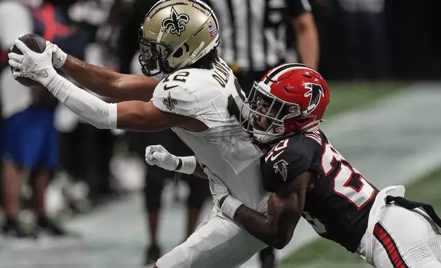 New Orleans Saints wide receiver Chris Olave (12) makes a catch against Atlanta Falcons cornerback Dee Alford (20) during the second half of an NFL football game, Sunday, Sept. 29, 2024, in Atlanta. (AP Photo/John Bazemore)