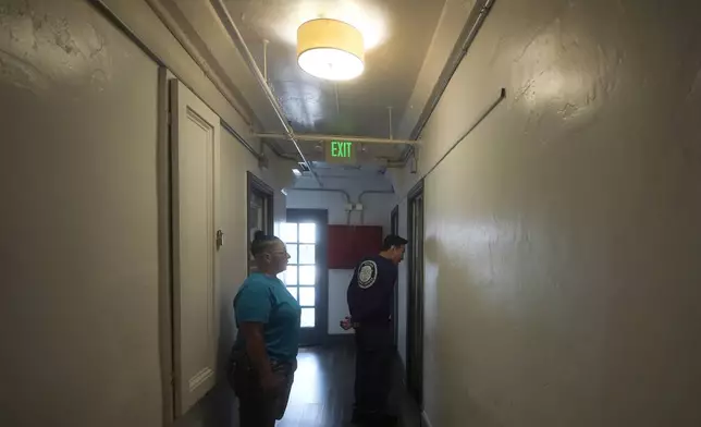 Brandi Marshall, Five Keys director of housing services, left, watches as Donald Siu, property manager, knocks on a resident's door at a Five Keys transitional housing location in San Francisco, Monday, Aug. 26, 2024. (AP Photo/Jeff Chiu)