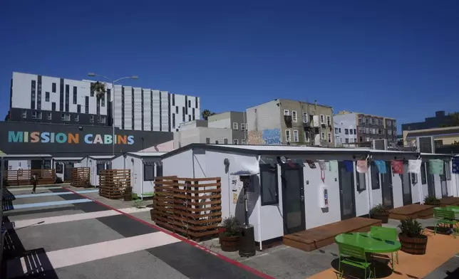 A person walks under a Mission Cabins sign at the Five Keys transitional housing location in San Francisco, Monday, Aug. 26, 2024. (AP Photo/Jeff Chiu)