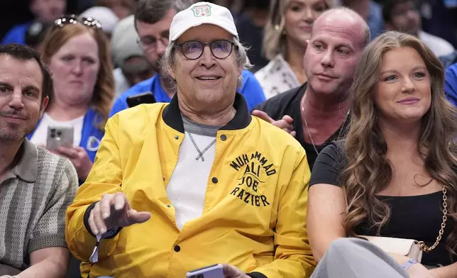 FILE - Actor Chevy Chase, center, sits on the front row during the second half of an NBA basketball game between the Atlanta Hawks and Dallas Mavericks in Dallas on April 4, 2024. (AP Photo/LM Otero, File)