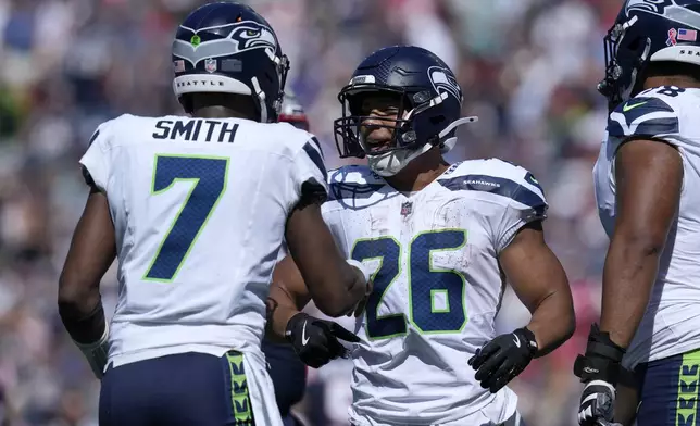 Seattle Seahawks quarterback Geno Smith (7) celebrates with running back Zach Charbonnet (26) after Charbonnet rushed for a touchdown in the first half of an NFL football game against the New England Patriots, Sunday, Sept. 15, 2024, in Foxborough, Mass. (AP Photo/Charles Krupa)