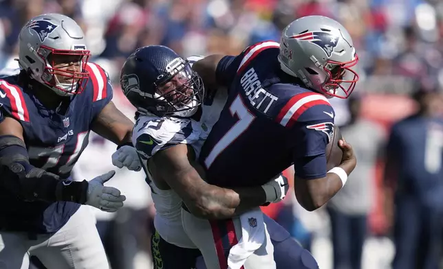 New England Patriots quarterback Jacoby Brissett, right, is sacked by Seattle Seahawks defensive end Leonard Williams, center, in front of Patriots guard Michael Jordan, left, in the second half of an NFL football game, Sunday, Sept. 15, 2024, in Foxborough, Mass. (AP Photo/Charles Krupa)