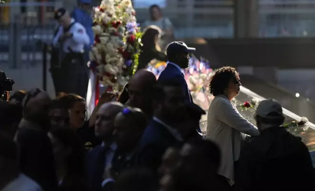 Ceremony attendees stand along the bronze parapets that border the reflecting pools during the 9/11 Memorial ceremony on the 23rd anniversary of the Sept. 11, 2001 terror attacks, Wednesday, Sept. 11, 2024, in New York. (AP Photo/Pamela Smith)