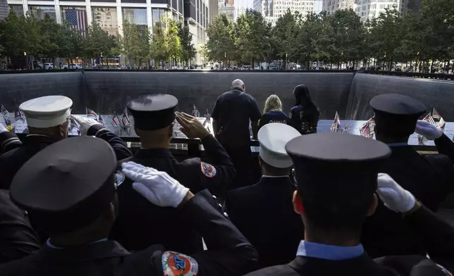 Firefighters salute during the moment of silence near the south pool during the 9/11 Memorial ceremony on the 23rd anniversary of the Sept. 11, 2001 attacks, Wednesday, Sept. 11, 2024, in New York. (AP Photo/Yuki Iwamura)