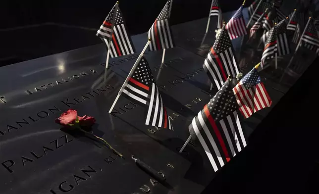 Flags and flowers are placed on the south reflecting pool during the 9/11 Memorial ceremony on the 23rd anniversary of the Sept. 11, 2001, attacks, Wednesday, Sept. 11, 2024, in New York. (AP Photo/Yuki Iwamura)