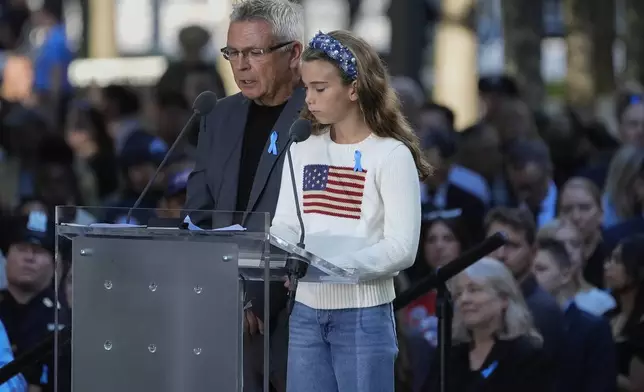 A man and a young girl read names of victims during the 9/11 Memorial ceremony on the 23rd anniversary of the Sept. 11, 2001 terror attacks, Wednesday, Sept. 11, 2024, in New York. (AP Photo/Pamela Smith)