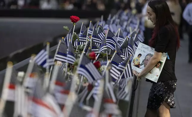 Mercedes Arias stands by the name of her father Joseph Amatuccio on the south pool during the 9/11 Memorial ceremony on the 23rd anniversary of the Sept. 11, 2001 attacks, Wednesday, Sept. 11, 2024, in New York. (AP Photo/Yuki Iwamura)