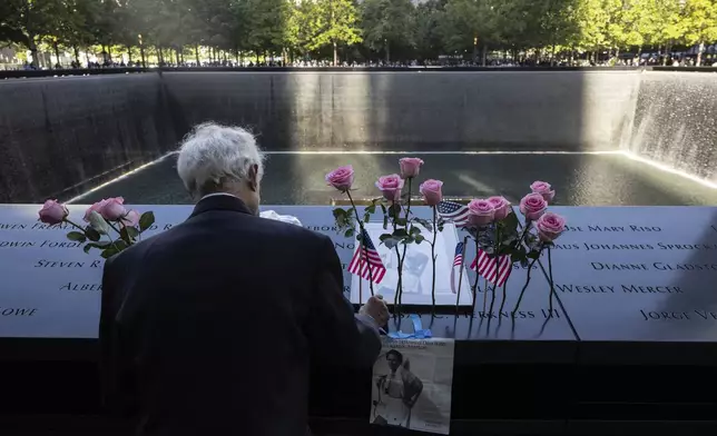 Hagi Abucar places flowers for his former coworker Lindsey Herkness on the south reflecting pool during the 9/11 Memorial ceremony on the 23rd anniversary of the Sept. 11, 2001 attacks, Wednesday, Sept. 11, 2024, in New York. (AP Photo/Yuki Iwamura)