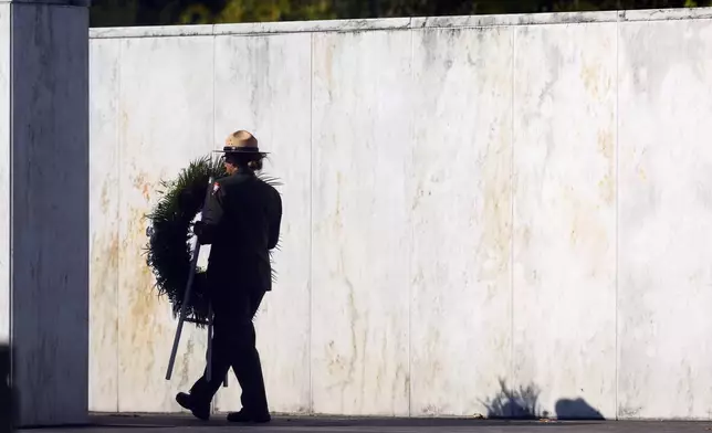 A member of the National Park Service brings a wreath out to the crash site at the Flight 93 National Memorial on the 23rd anniversary of the Sept. 11, attacks in Shanksville, Pa., Wednesday, Sept. 11, 2024. (AP Photo/Jared Wickerham)