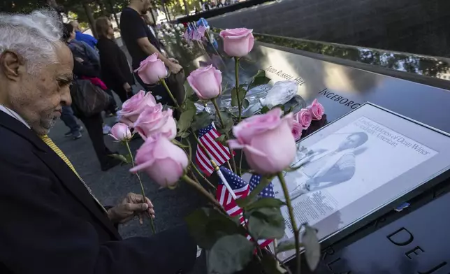 Hagi Abucar, left, places flowers for his former coworker Lindsey Herkness on the south pool during the 9/11 Memorial ceremony on the 23rd anniversary of the Sept. 11, 2001 attacks, Wednesday, Sept. 11, 2024, in New York. (AP Photo/Yuki Iwamura)