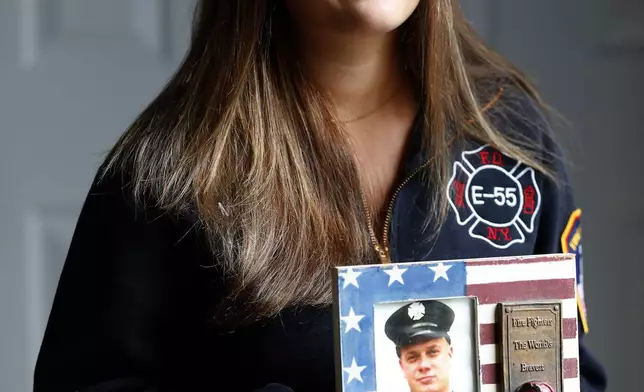 Capri Yarosz holds a photo of New York firefighter Christopher Michael Mozzillo, Saturday, Sept. 7, 2024, in Freehold, N.J.. Mozzillo, who died in the 9/11 attacks, was Yarosz's uncle. (AP Photo/Noah K. Murray)