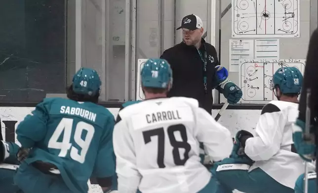 San Jose Sharks head coach Ryan Warsofsky, rear, gives instruction at the NHL hockey team's practice facility in San Jose, Calif., Thursday, Sept. 19, 2024. (AP Photo/Jeff Chiu)