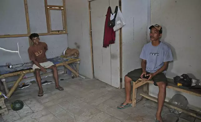 Andika Yudha Agusta, right, and his brother Dias Yudho Prihantoro who work together at a shrimp farm sit inside the hut where they stay during their work shifts at the farm in Kebumen, Central Java, Indonesia, Tuesday, Sept. 24, 2024. (AP Photo/Dita Alangkara)