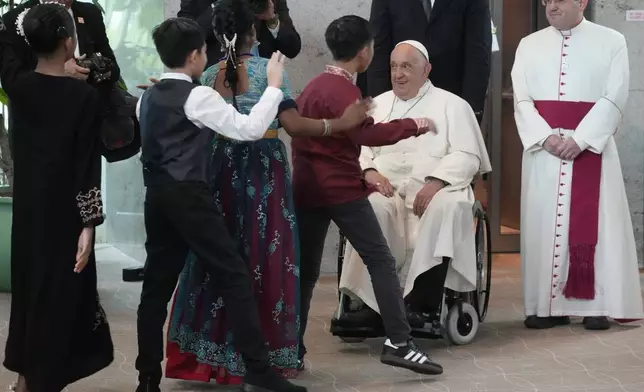 Pope Francis is welcomed by dancing children as he arrives at Singapore Changi International Airport, Wednesday, Sept. 11, 2024. Pope Francis is heading to Singapore for the final leg of his 11-day trip to Asia and Oceania. (AP Photo/Gregorio Borgia)