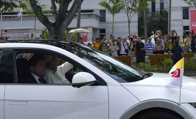 Pope Francis in a car, waves as he leaves from the Parliament House in Singapore, Thursday, Sept. 12, 2024. (AP Photo/Vincent Thian)