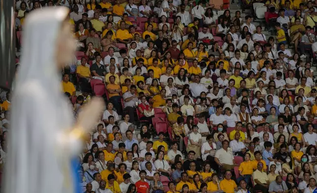 Faithful wait in the Singapore SportsHub National Stadium where Pope Francis will preside over a mass 'In Memory of the Most Holy Name of Mary' celebrated by the Archbishop of Singapore, Cardinal William Goh Seng Chye, Thursday, Sept. 12, 2024. Pope Francis has praised Singapore's economic development as a testament to human ingenuity. But he's urging the city-state to look after the weakest too. Francis made the remarks Thursday on the final leg of the longest and farthest tour of his papacy. At left a statue of the Holy Mary. (AP Photo/Gregorio Borgia)