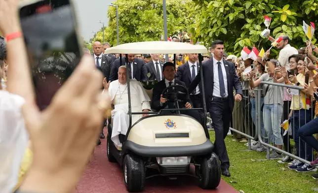 Pope Francis travels in a buggy as he greets the volunteers on his arrival in Singapore, Wednesday, Sept. 11, 2024. (AP Photo/Vincent Thian)