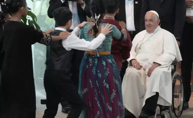 Pope Francis is welcomed by dancing children as he arrives at Singapore Changi International Airport, Wednesday, Sept. 11, 2024. Pope Francis is heading to Singapore for the final leg of his 11-day trip to Asia and Oceania. (AP Photo/Gregorio Borgia)