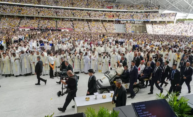 Faithful wait in the Singapore SportsHub National Stadium where Pope Francis will preside over a mass 'In Memory of the Most Holy Name of Mary' celebrated by the Archbishop of Singapore, Cardinal William Goh Seng Chye, center right, Thursday, Sept. 12, 2024. Pope Francis has praised Singapore's economic development as a testament to human ingenuity. But he's urging the city-state to look after the weakest too. Francis made the remarks Thursday on the final leg of the longest and farthest tour of his papacy. (AP Photo/Gregorio Borgia)