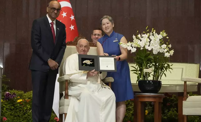 Chief Executive Officer of the Singapore's National Parks Board Hwang Yu-Ning, right, and Singapore's President Tharman Shanmugaratnam, left, present Pope Francis with a 'Dendrobium His Holiness Pope Francis', a specially bred orchid variety named after him in honor of his visit to Singapore during a welcome ceremony at the Parliament House in Singapore, Thursday, Sept. 12, 2024. Pope Francis flew to Singapore on Wednesday for the final leg of his trip through Asia, arriving in one of the world's richest countries from one of its poorest after a record-setting final Mass in East Timor. (AP Photo/Gregorio Borgia)