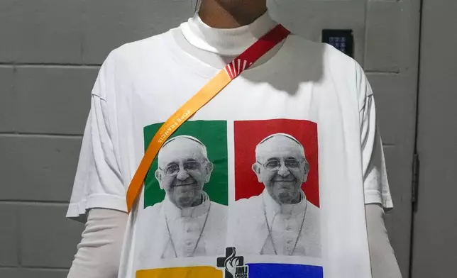 A woman shows a celebrative t-shirt as she waits in the Singapore SportsHub National Stadium where Pope Francis will preside over a mass 'In Memory of the Most Holy Name of Mary' celebrated by the Archbishop of Singapore, Cardinal William Goh Seng Chye, Thursday, Sept. 12, 2024. Pope Francis has praised Singapore's economic development as a testament to human ingenuity. But he's urging the city-state to look after the weakest too. Francis made the remarks Thursday on the final leg of the longest and farthest tour of his papacy. (AP Photo/Gregorio Borgia)