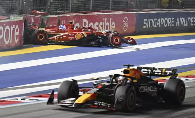 Ferrari driver Carlos Sainz of Spain leaves after he crashed into the track wall as Red Bull driver Max Verstappen of the Netherlands, bottom, steers his car during the qualifying session of the Singapore Formula One Grand Prix at the Marina Bay Street Circuit, in Singapore, Saturday, Sept. 21, 2024. (Mohd Rasfan/Pool Photo via AP)