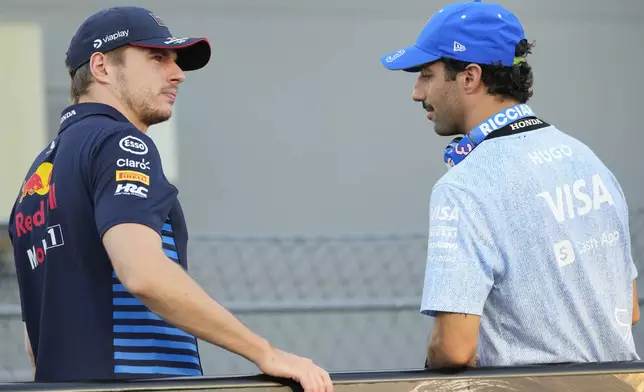 Red Bull driver Max Verstappen, left, of the Netherlands and RB driver Daniel Ricciardo of Australia talk during the drivers parade ahead of the Singapore Formula One Grand Prix at the Marina Bay Street Circuit, in Singapore, Sunday, Sept. 22, 2024. (AP Photo/Vincent Thian)