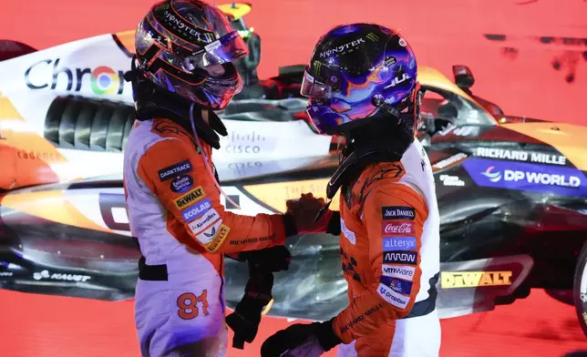 McLaren driver Lando Norris of Britain is congratulated by teammate Oscar Piastri, left, of Australia after winning the Singapore Formula One Grand Prix at the Marina Bay Street Circuit, in Singapore, Sunday, Sept. 22, 2024. (AP Photo/Vincent Thian)