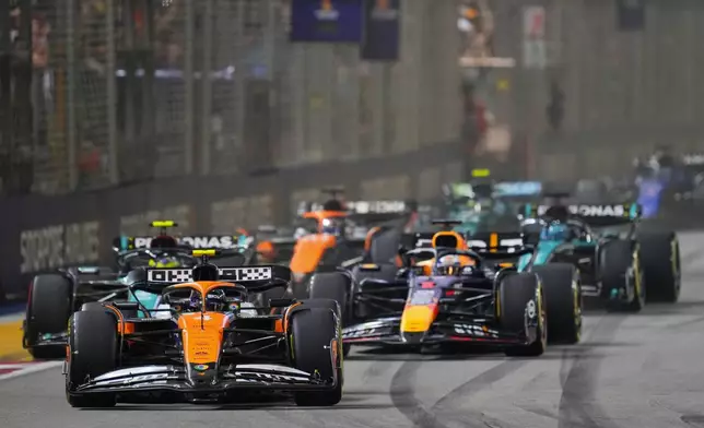 McLaren driver Lando Norris, left, of Britain leads Red Bull driver Max Verstappen of the Netherlands into turn one at the start of the Singapore Formula One Grand Prix at the Marina Bay Street Circuit, in Singapore, Sunday, Sept. 22, 2024. (AP Photo/Vincent Thian)