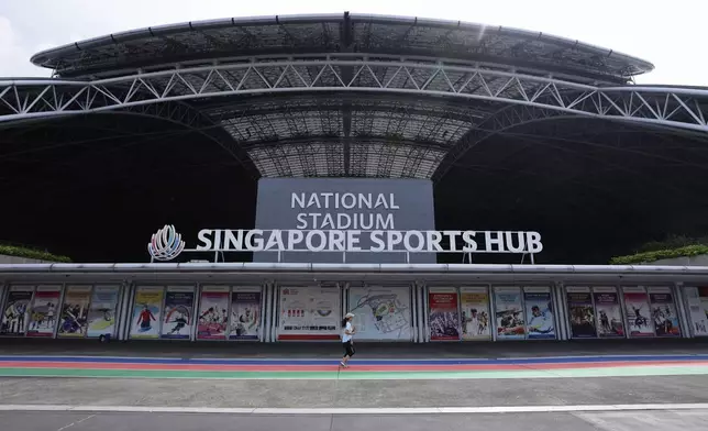 A woman jogs along the promenade of the National Stadium in Singapore, Sunday, Sept. 8, 2024. (AP Photo/Suhaimi Abdullah)