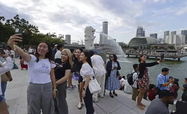 People take photos at Merlion Park in Singapore, Saturday, Sept. 7, 2024. (AP Photo/Suhaimi Abdullah)