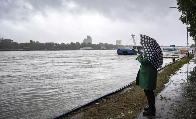 A woman takes a photo of high levels of the Danube river in Bratislava, Slovakia, Sunday, Sept. 15, 2024. (AP Photo/Tomas Hrivnak)